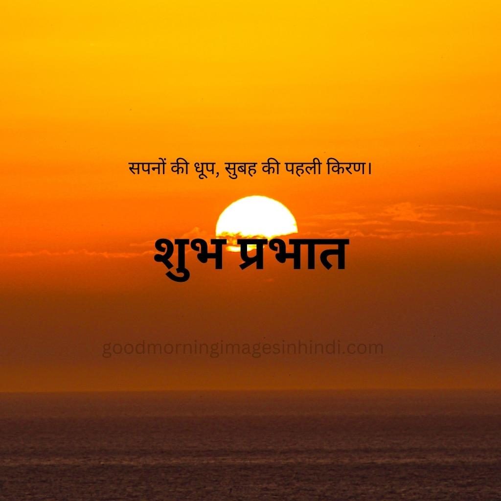 Shubh Prabhat! A single yellow sun hangs low in the sky, casting long shadows across a mountain range and wispy clouds good morning images in hindi